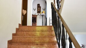 Una escalera de mármol conduce a una habitación con una botellera, un reloj y un adorno con forma de corazón.
