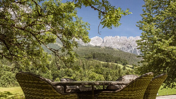 Sillas de mimbre con vistas a un paisaje montañoso.