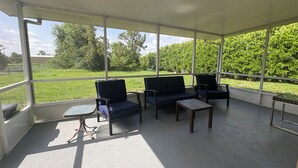 A covered patio with two blue sofas, a small table, and a glass table.