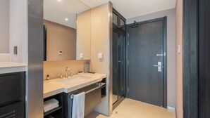 Ein modernes Badezimmer mit zwei Waschbecken, einem großen Spiegel und einer dunklen Tür.
