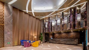 Eine moderne Lobby mit Empfangsschalter, Sitzgelegenheiten und einer Treppe.