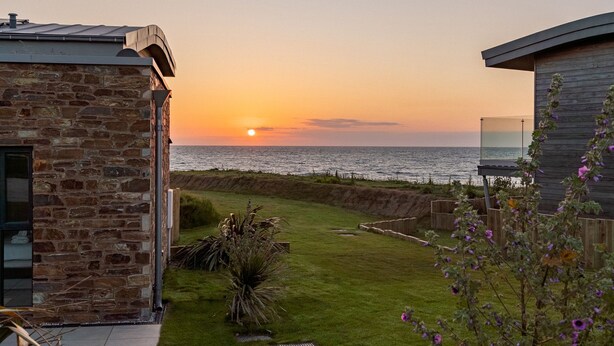Un edificio de piedra con vistas a la puesta de sol sobre el mar.