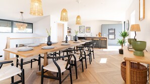 Un comedor moderno con una larga mesa de madera, sillas negras y lámparas colgantes de mimbre.