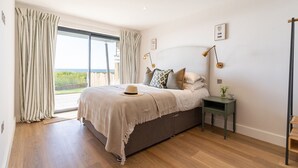 Un dormitorio con una cama grande, una mesita de noche y vistas al exterior.