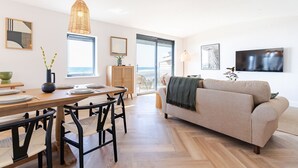 Una sala de estar moderna con sofá, mesa de comedor, sillas, televisor y obras de arte en las paredes.