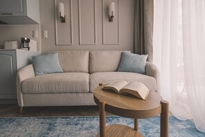 A neutral-toned sofa with a coffee machine and a small table with an open book. - Modern Comfort in Nowy Port (Bydgoszcz)
