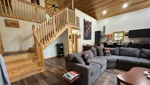 A spacious living area with a wooden staircase, a sectional sofa, and a dining area.