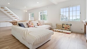 A spacious room with a large bed, a sofa, and a dining area with a staircase.