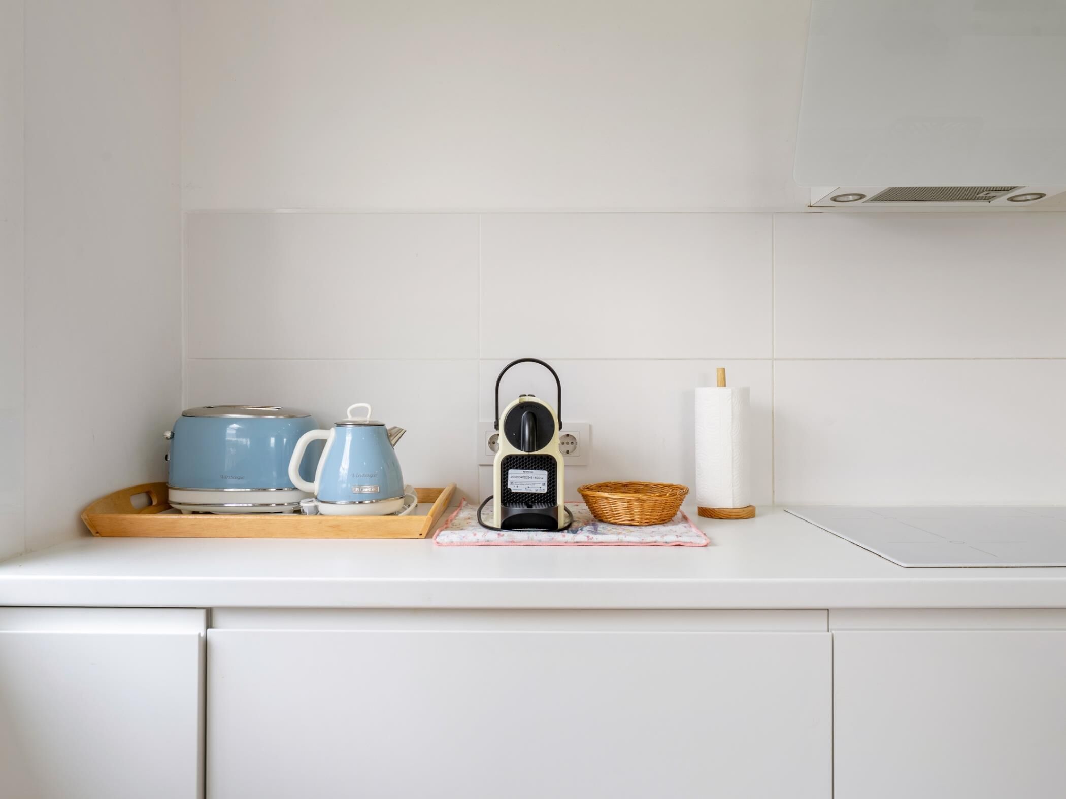 Una cocina con tostadora, hervidor, tetera eléctrica y una cesta sobre la encimera.
