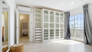 A spacious room with a large window, a built-in wardrobe, and a ceiling fan.