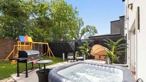A backyard with a hot tub, a swing set, and a barbecue grill. - Spacious 4-bedroom house Game Room & Spa in fantastic Dallas 11 (Dallas)