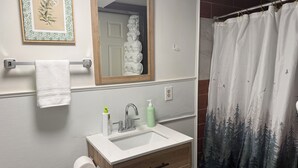 Ein Badezimmer mit einem weißen Waschbecken, einem Spiegel, einem Handtuchhalter und einer Duschvorhang.