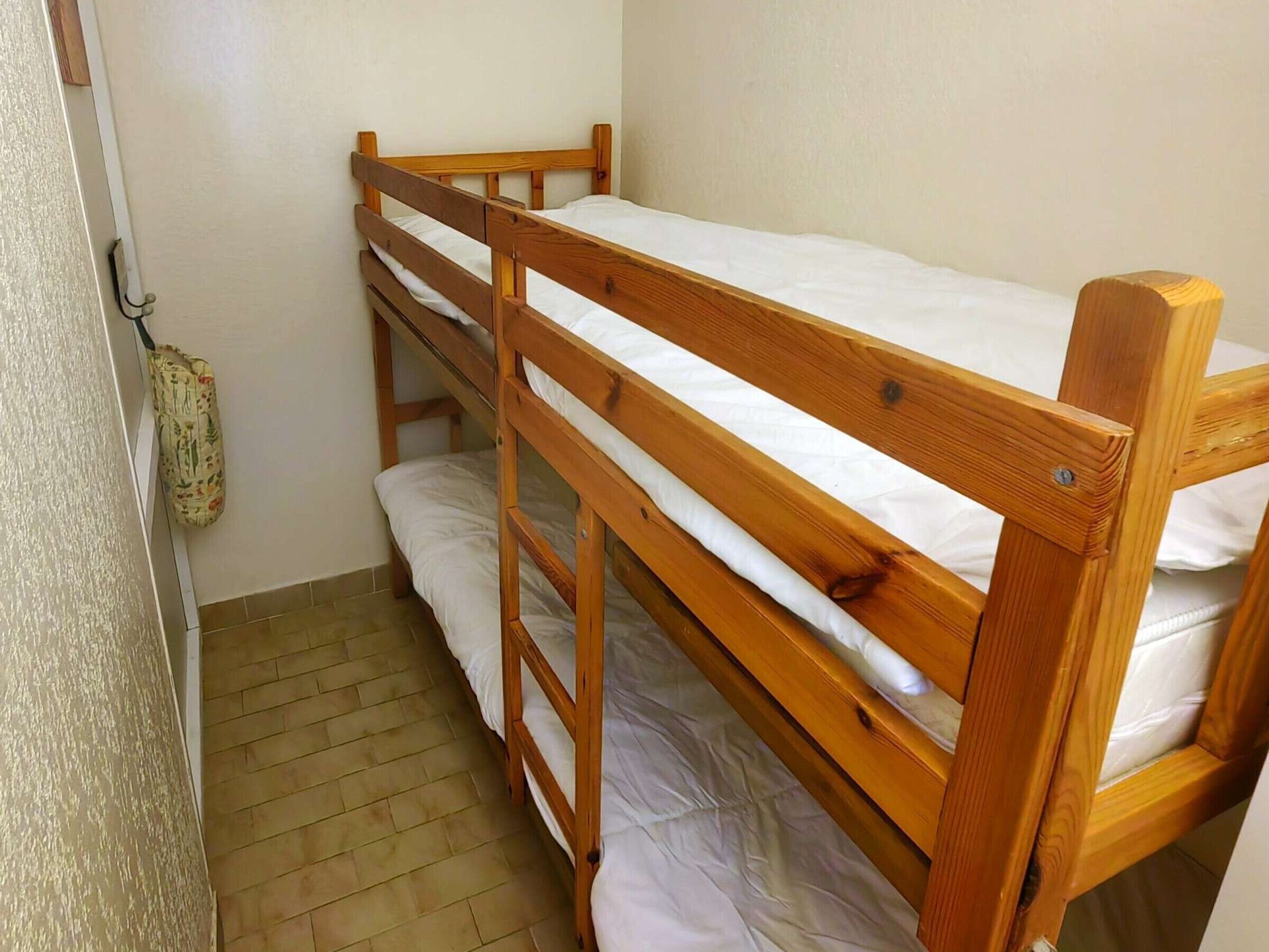 A bunk bed room with wooden frames and white bedding.