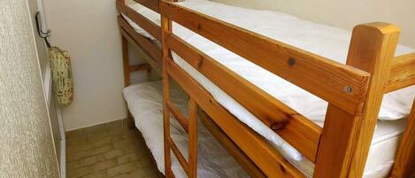 A bunk bed room with wooden frames and white bedding.
