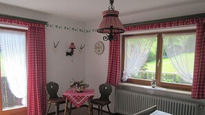 Una habitación con cama, una mesa con sillas, un reloj y una ventana con cortinas.