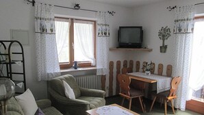 Una sala de estar acogedora con un sofá verde, una mesa de madera y un televisor.