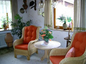 Une pièce avec des chaises en osier, une petite table ronde et une fenêtre donnant sur l’extérieur.