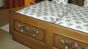 Un dormitorio con cama de madera, ropa de cama floral, una mesita de noche, una lámpara y un armario.