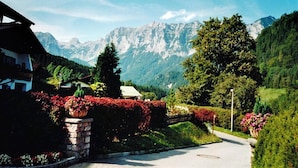 A mountain view with a road leading to a building with a sloped roof. - Apartment 3, 1-2 persons, 40 sqm, shower/WC, balcony, TV, 1 bedroom, non-smoking, south-facing (Ramsau bei Berchtesgaden)