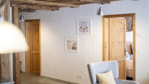 A hallway with wooden doors, a framed picture on the wall, and a chair in the foreground. - Chasa Rustica – Modern 3-Room Apartment with Traditional Charm in Sent (Sent)