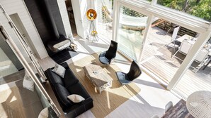 A modern living room with a black leather sofa, a wooden coffee table, and a glass door leading to an outdoor deck. - Lagunen Villa 3 by Interhome (Hölick)