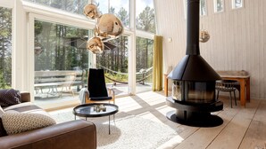 Een moderne woonkamer met een groot raam, een zwarte houtkachel en een gezellige zithoek.