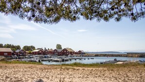 Een kustjachthaven met rode gebouwen, boten en een zandstrand.