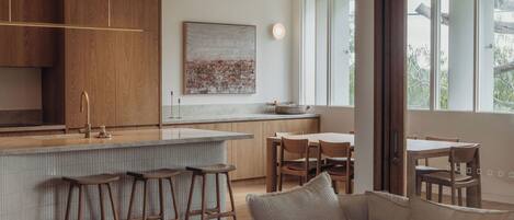 A modern kitchen with wooden cabinets, a bar area with stools, and a dining area with a table and chairs.
