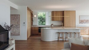 Eine moderne Küche mit Holzschränken, einer gewölbten Kochinsel mit Barhocker und einem großen Fenster für natürliches Licht.