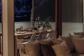 An outdoor dining area with a table set for two, surrounded by cushioned chairs. - Osprey at Hawks Nest - Entire Property (Hawks Nest)