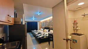 A hotel room with a kitchenette, a bed with a headboard, a dining area, and a bathroom with a sink and a water dispenser. - Cozy 1-bedroom condo in beautiful Pasay City with WiFi, AC (Pasay city)