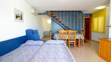 A bedroom with a bed, a desk, and a chair. There is a staircase leading to another room.