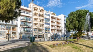 Un hotel de varios pisos con balcones, una fuente y un jardín ajardinado.