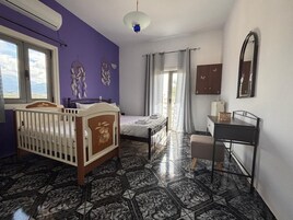 Une chambre avec un berceau, un lit, un bureau et une armoire.