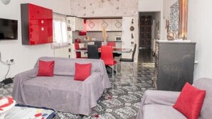 Un espacio habitable compacto con kitchenette, comedor y un conjunto de sofás.