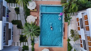 An aerial view of a modern pool area with a rectangular pool, surrounded by wooden decking and palm trees. - The R&B Boutique (Kampot)