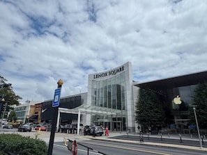Un immeuble de Lenox Square doté d’une façade en verre, avec un ciel dégagé et un parking où sont stationnées des voitures.