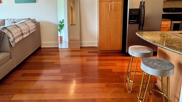 A modern kitchen with wooden cabinets, a stainless steel refrigerator, and a built-in microwave. There is a bar area with stools and a potted plant. - FIFA World Cup - SuiteHearts Buckhead (Atlanta)
