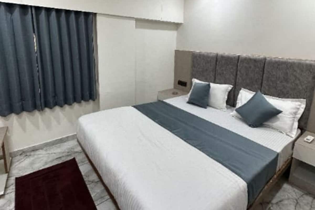 A bedroom with a bed, a nightstand, a ceiling fan, and a window with curtains.