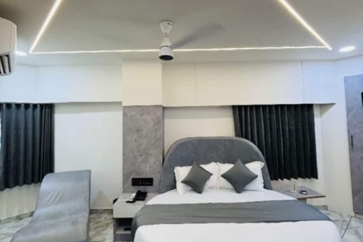 A modern bedroom with a large bed, a bedside table, a nightstand, a ceiling fan, and a headboard.