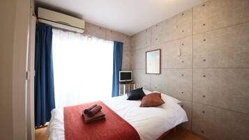 Una habitación de hotel con cama, televisión, aire acondicionado y una ventana con cortinas.