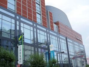 Ein modernes Gebäude mit großen Glasfenstern, einem gewölbten Dach und Beschilderung für SMBC Sumitomo Mitsui Banking Corporation und Carrot Tower.