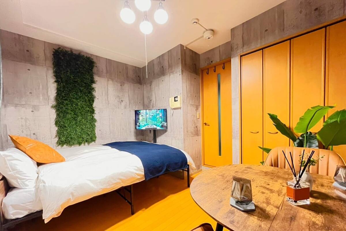 Una habitación con una cama, un televisor, una mesa de madera y una planta.