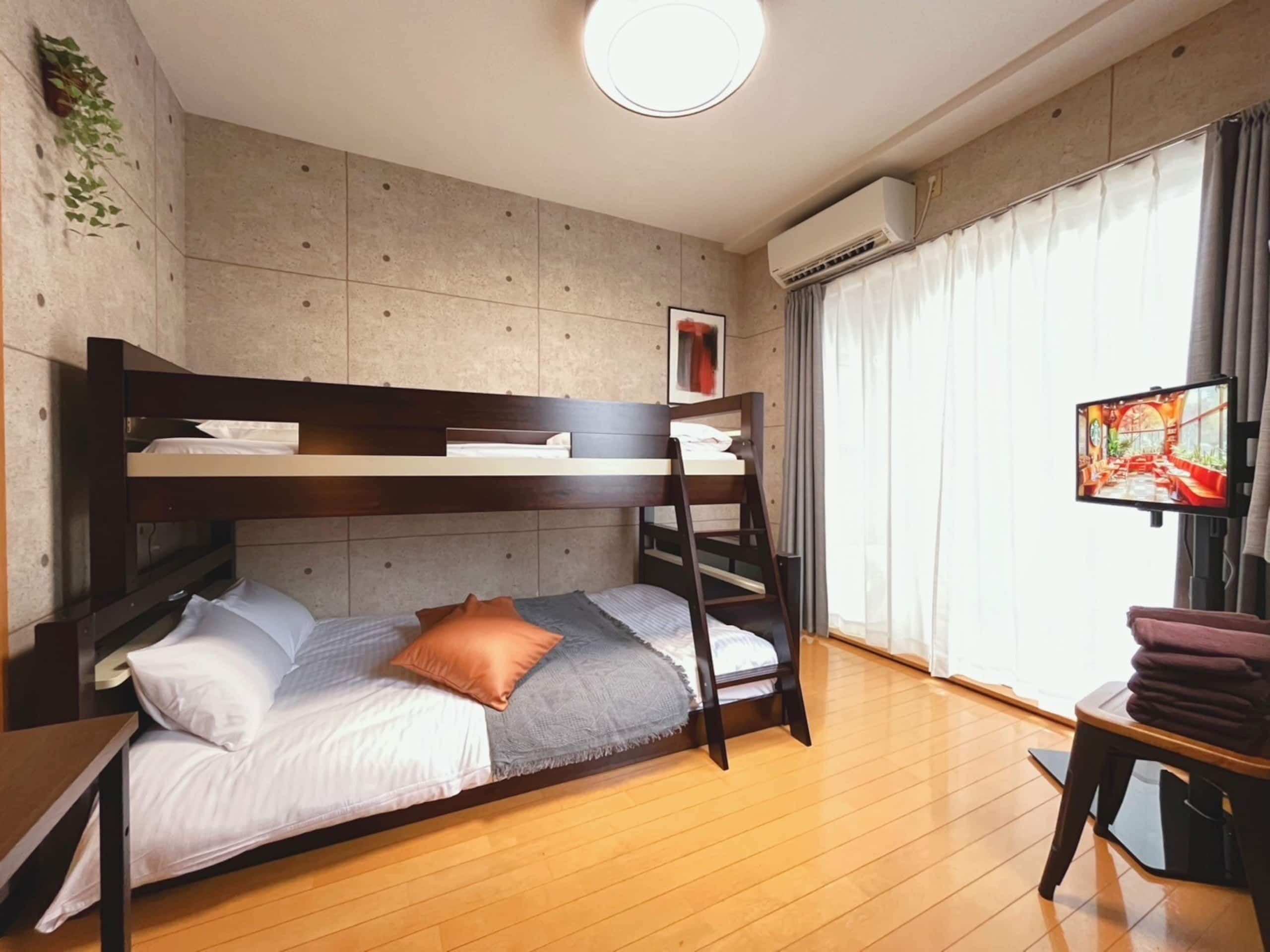 Dormitorio con literas, escritorio y televisor.