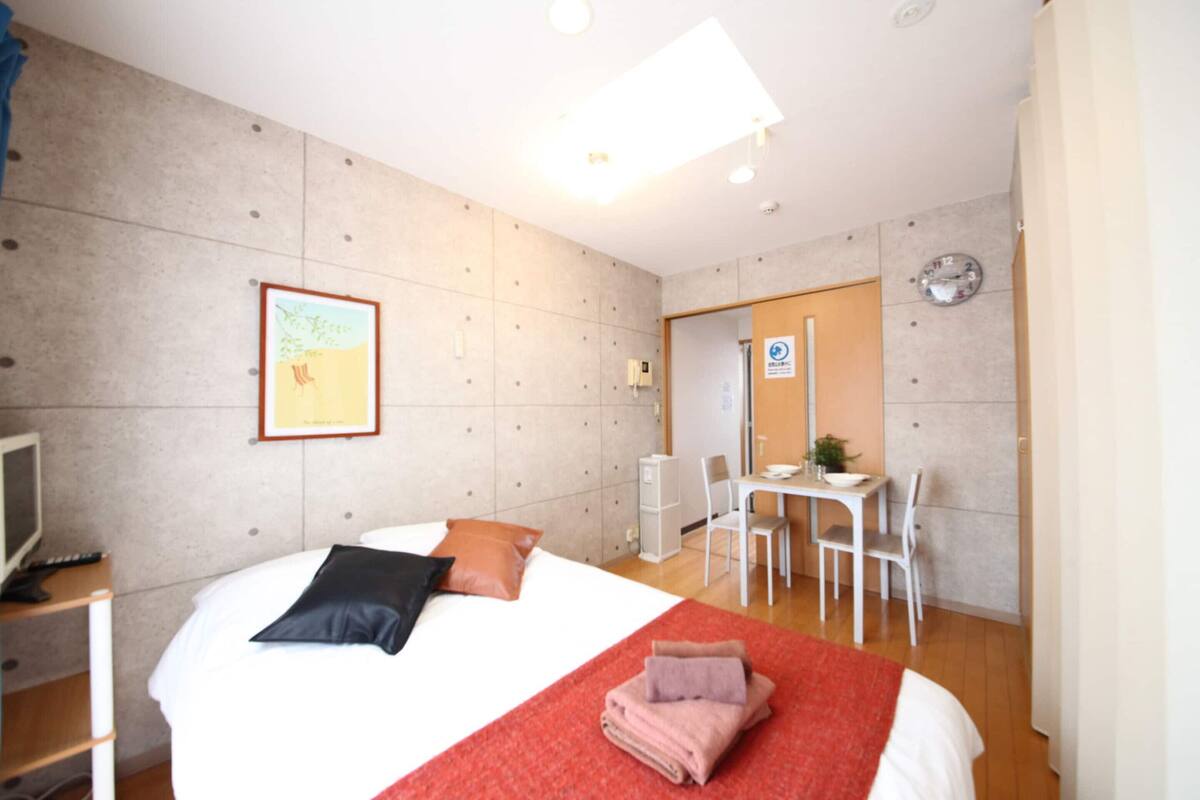 Habitación de hotel con cama, escritorio, silla, televisión y un cuadro en la pared.