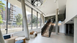 En modern inredning med en trappa, stora fönster och minimalistiska sittmöbler.