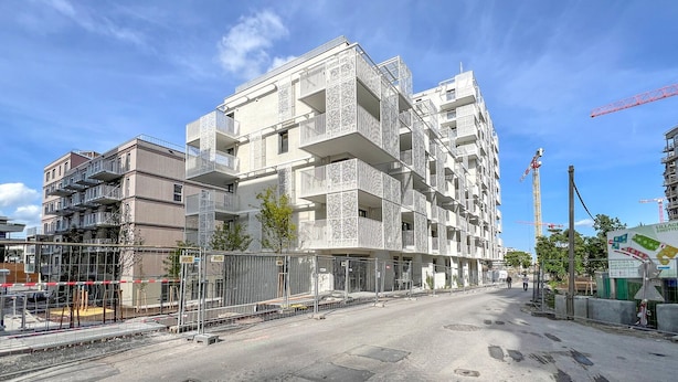 En byggnad med flera våningar som är under uppförande, med balkonger och en byggarbetsplats i förgrunden.