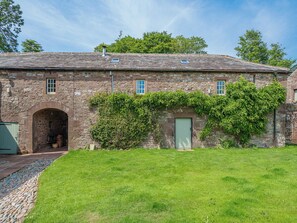 A stone building with a green door, an arched entrance, and a grassy yard. - 2 bedroom accommodation in Carlisle (Carlisle)