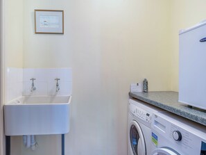 A laundry area with a washing machine, a sink, and a framed picture on the wall. - 2 bedroom accommodation in Carlisle (Carlisle)