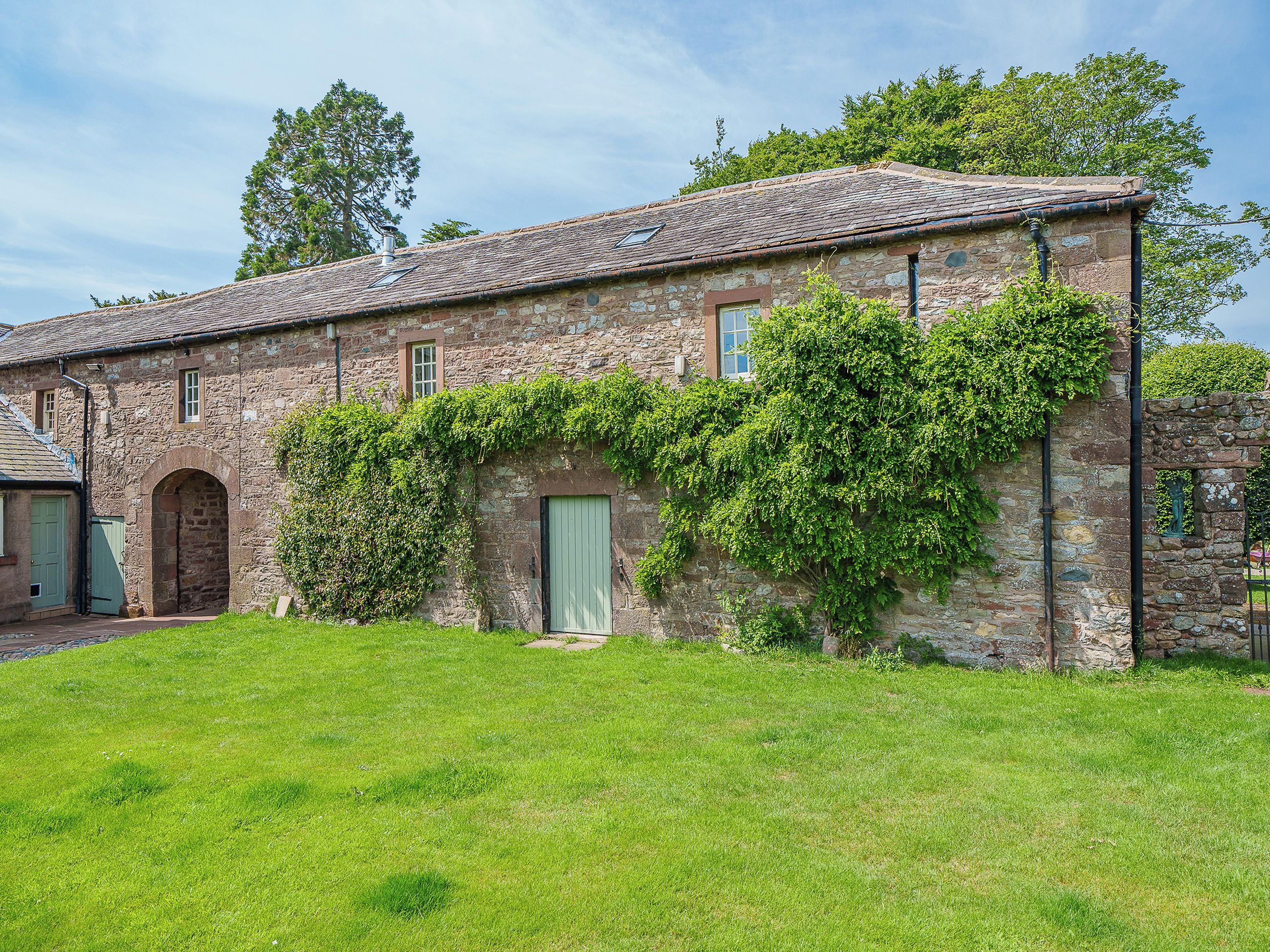 A stone building with a tiled roof, a green door, and a small arched window.